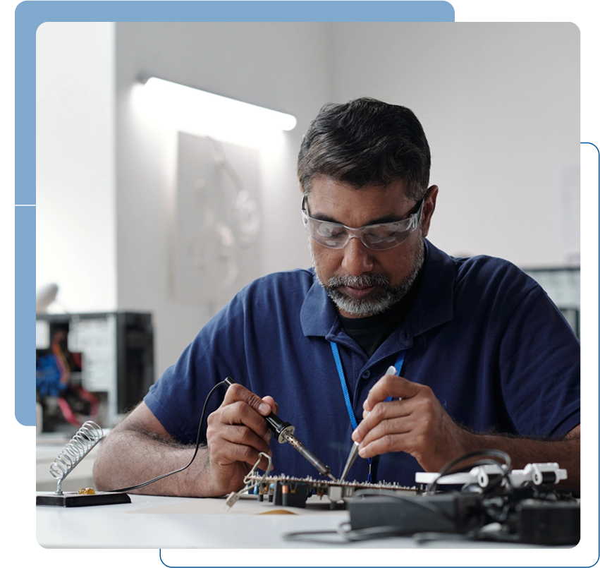 Man soldering electronic components at desk.